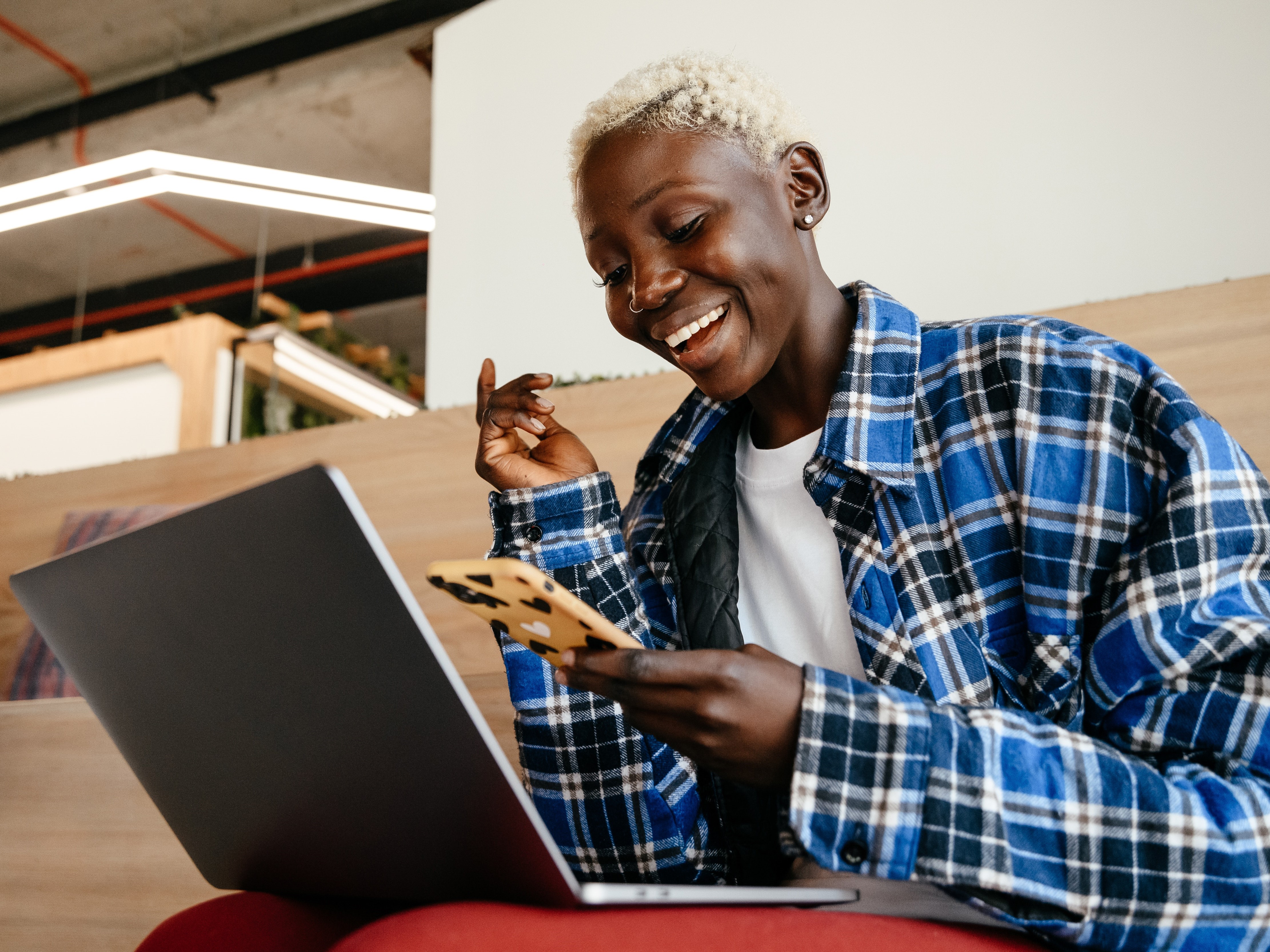 student checking their phone while studying on a laptop